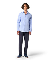 Man wearing a light blue button-up shirt and dark pants 