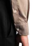 Close-up of a person wearing a brown shirt with rolled-up sleeves on a black background