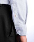 Close-up of a light blue shirt with rolled-up sleeves and dark pants on a white background