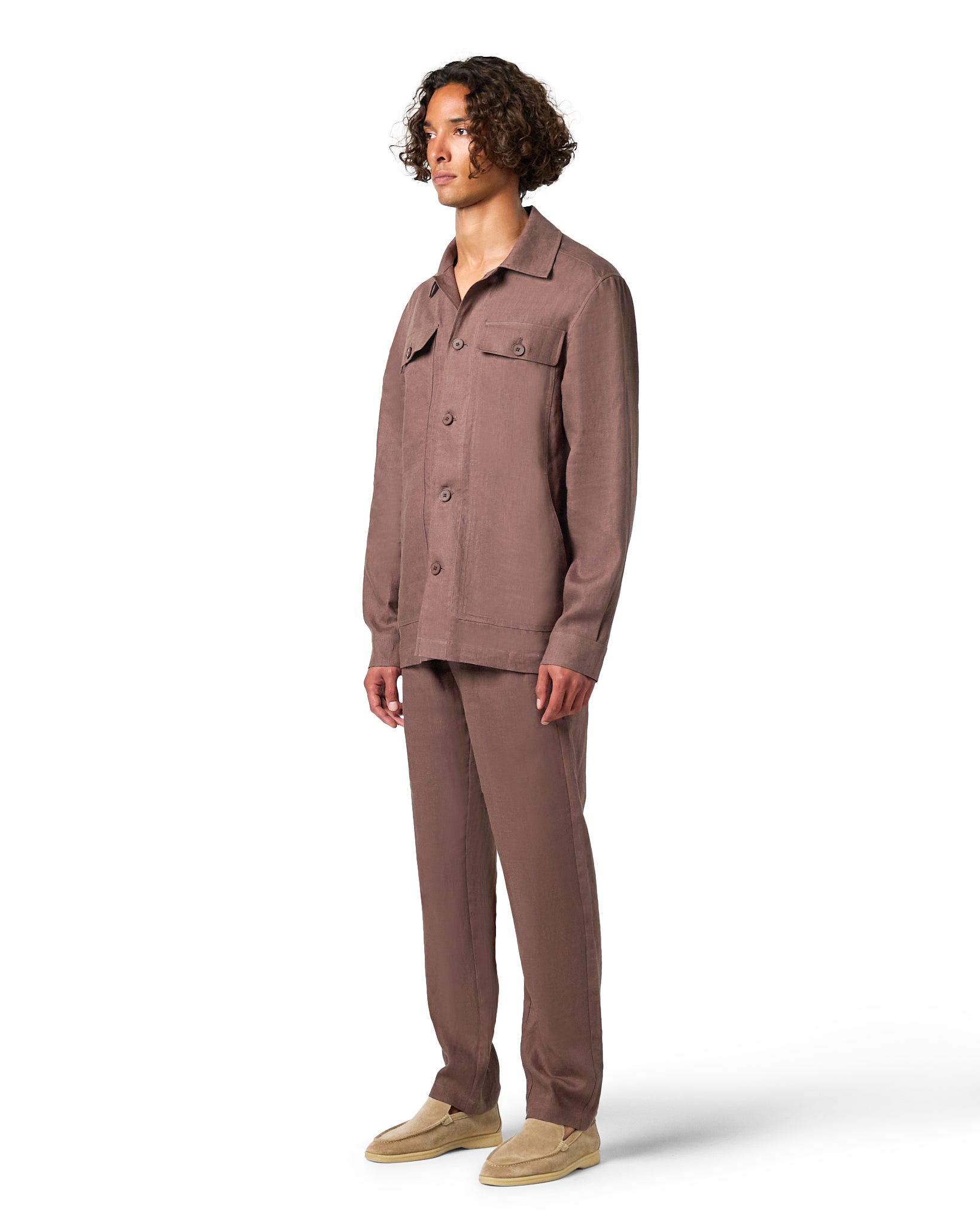 Man wearing a brown button-up shirt and pants on a white background