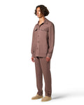 Man wearing a brown button-up shirt and pants on a white background