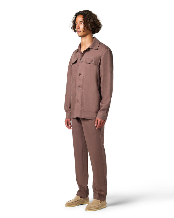 Man wearing a brown button-up shirt and pants on a white background