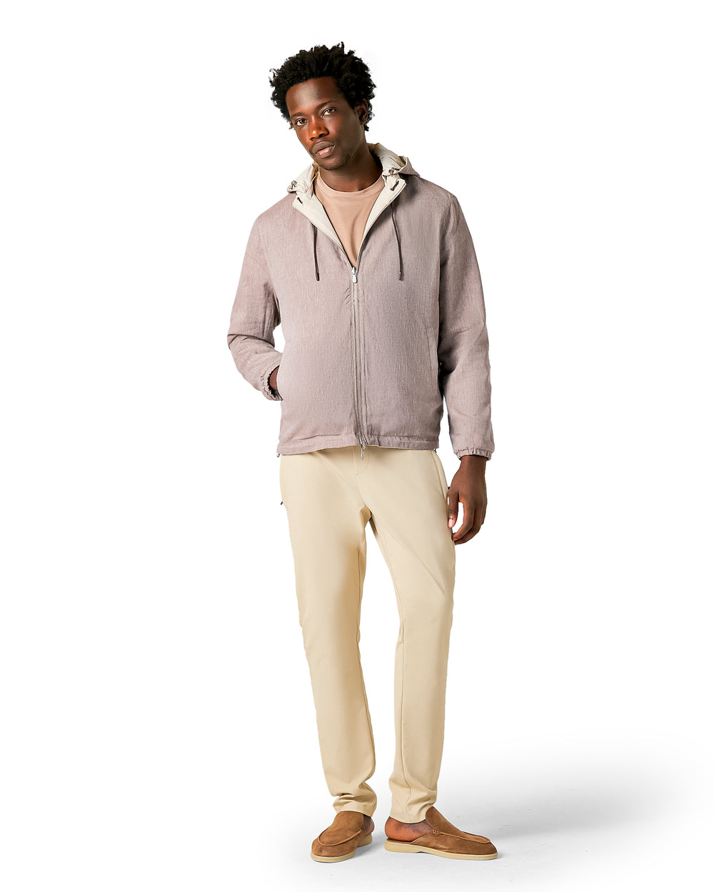 Man wearing a light brown jacket and beige pants on a white background