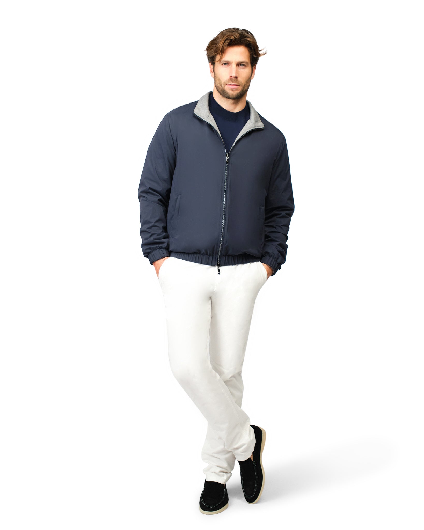 Man wearing a navy jacket and white pants on a white background