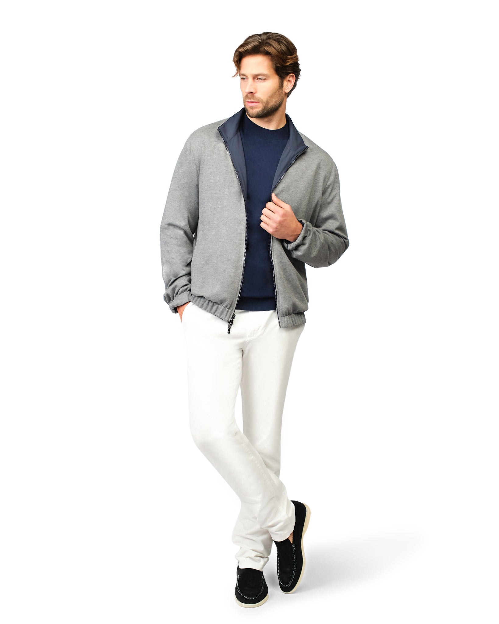 Man wearing a gray jacket, navy shirt, white pants, and black shoes on a white background