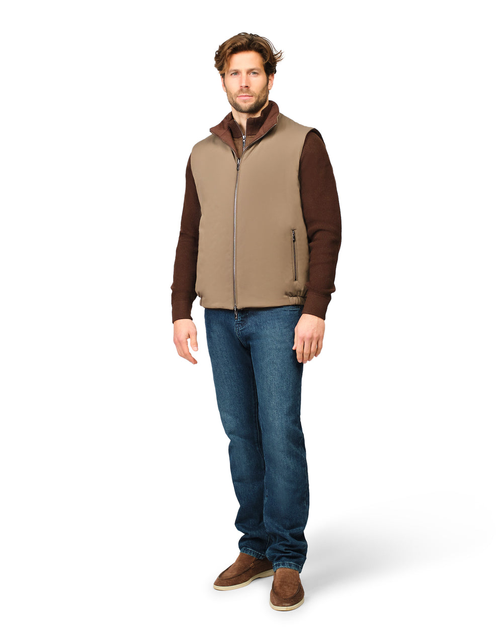 Man wearing a brown vest over a brown shirt with blue jeans on a white background