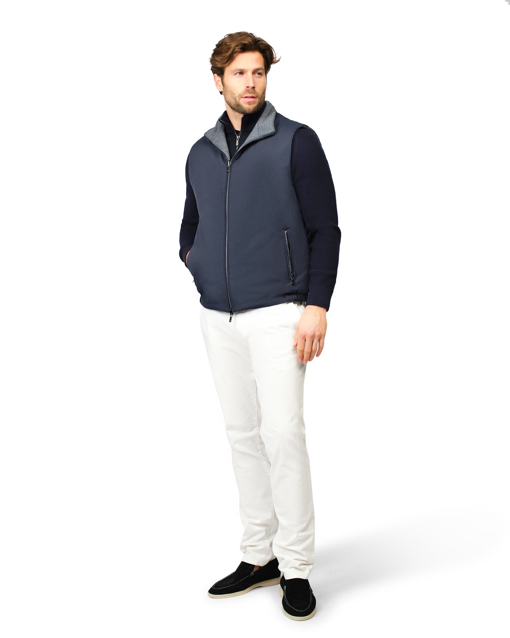 Man wearing a navy two-tone jacket and white pants on a white background