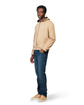 Man wearing a beige jacket and blue jeans on a white background