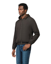 Man wearing a dark brown jacket and blue jeans on a white background