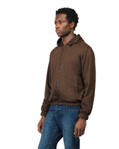 Man wearing a brown jacket and blue jeans on a white background