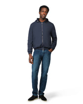 Man wearing a navy blue jacket and jeans on a white background