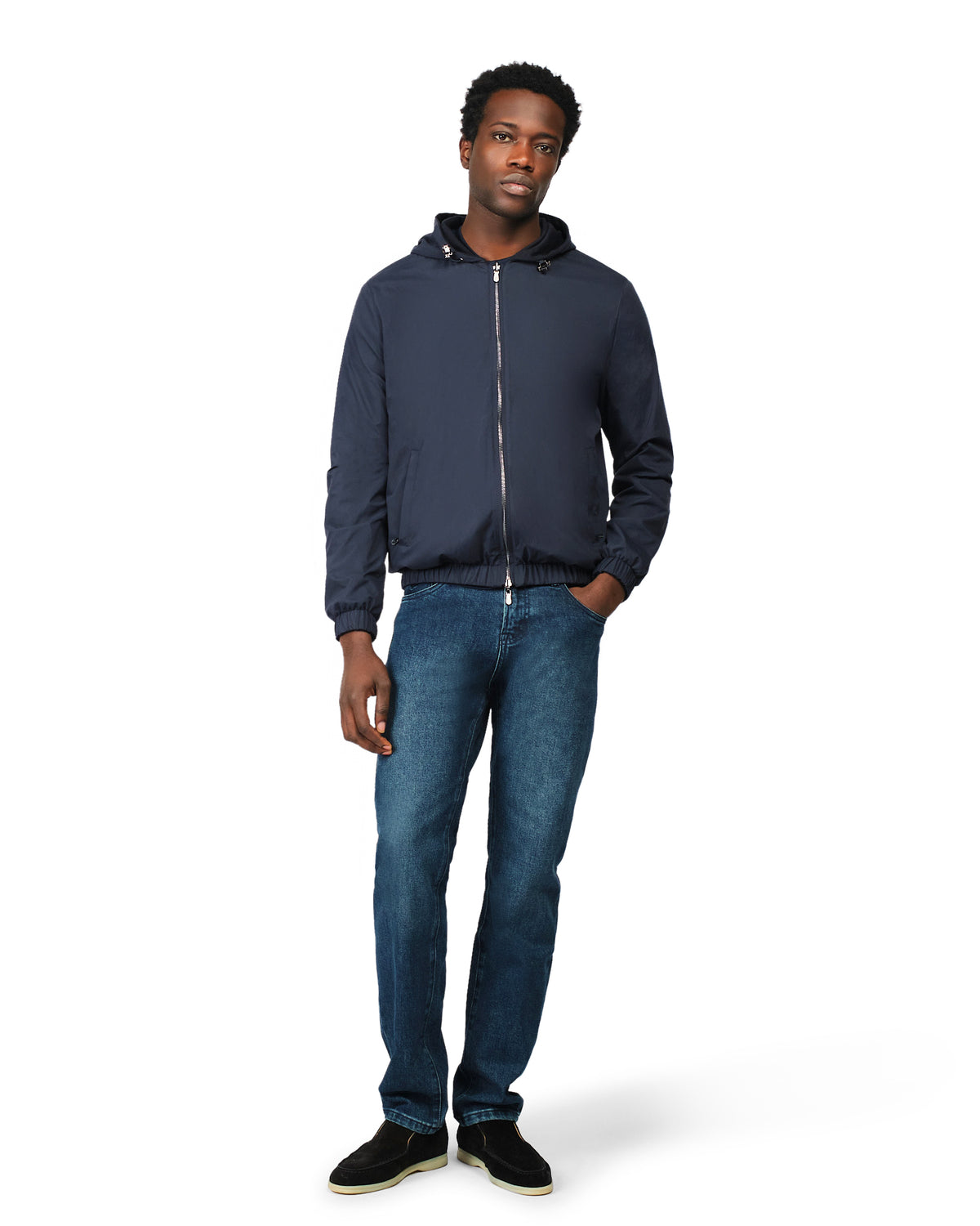 Man wearing a navy blue jacket and jeans on a white background