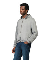 Man wearing a gray hoodie and blue jeans on a white background