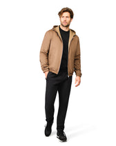 Man wearing a brown jacket and black pants on a white background