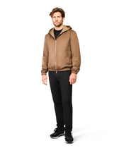 Man wearing a brown jacket and black pants on a white background