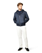 Man wearing a navy jacket and white pants on a white background