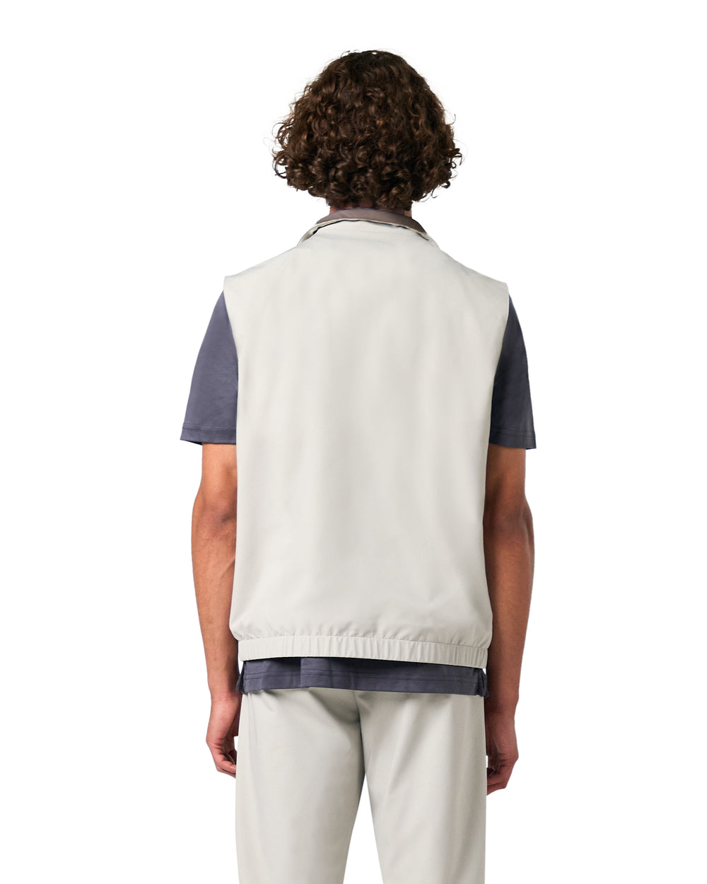 Person wearing a light-colored vest over a dark shirt on a white background