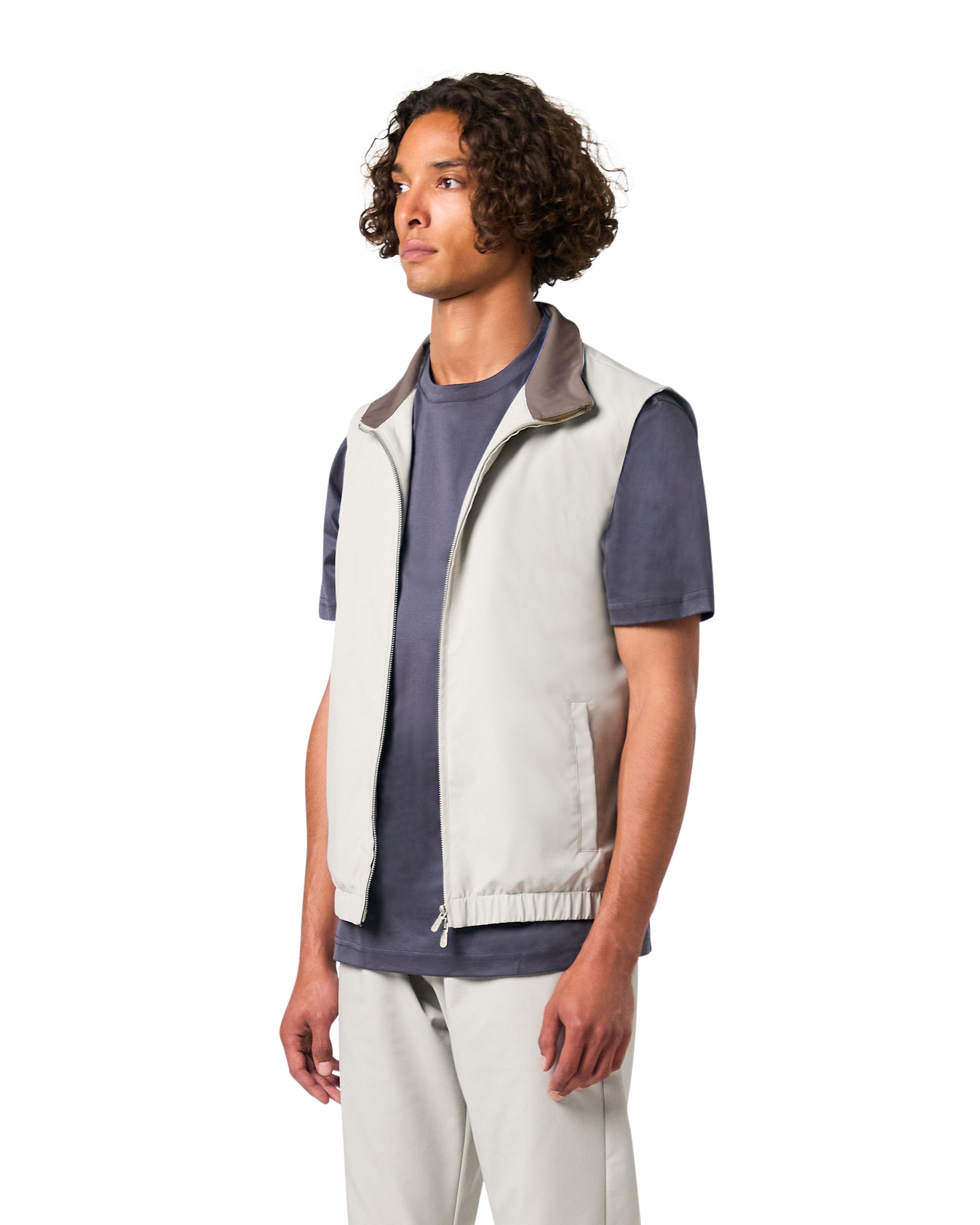 Person wearing a light gray vest over a dark shirt on a white background