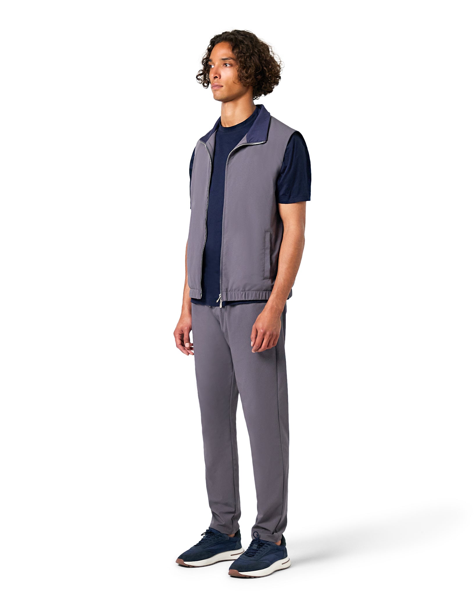 Man wearing a gray vest and pants with a navy shirt on a white background