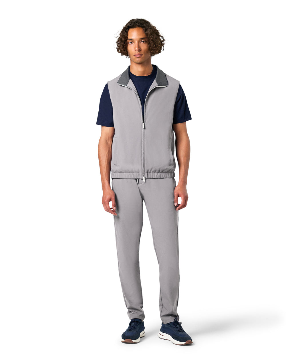 Man wearing a gray vest and pants with navy shirt on a white background