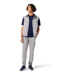 Person wearing a gray vest over a navy shirt with gray pants on a white background