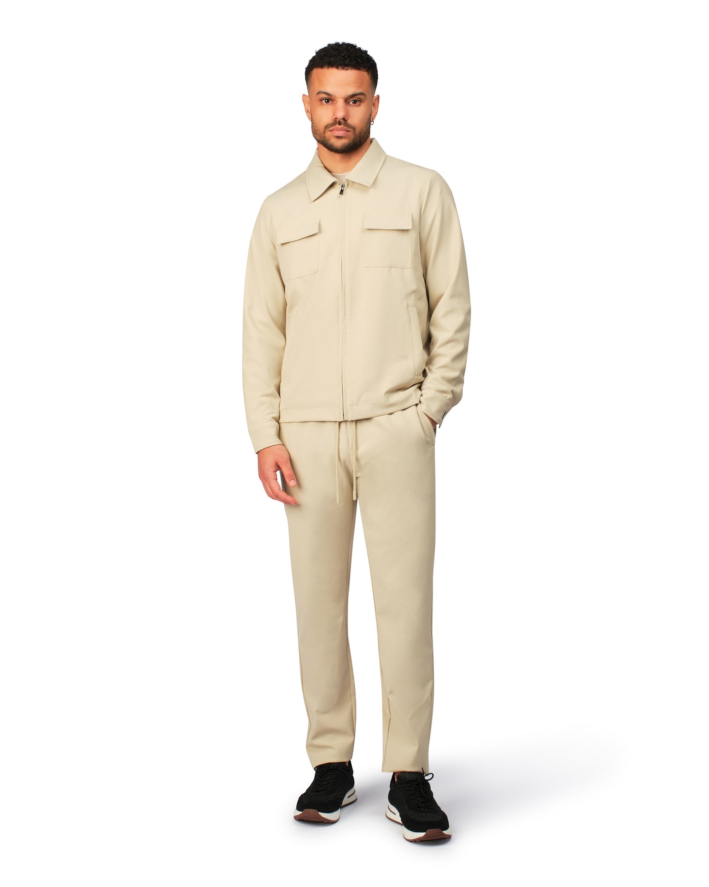 Man wearing a beige jacket and pants on a white background