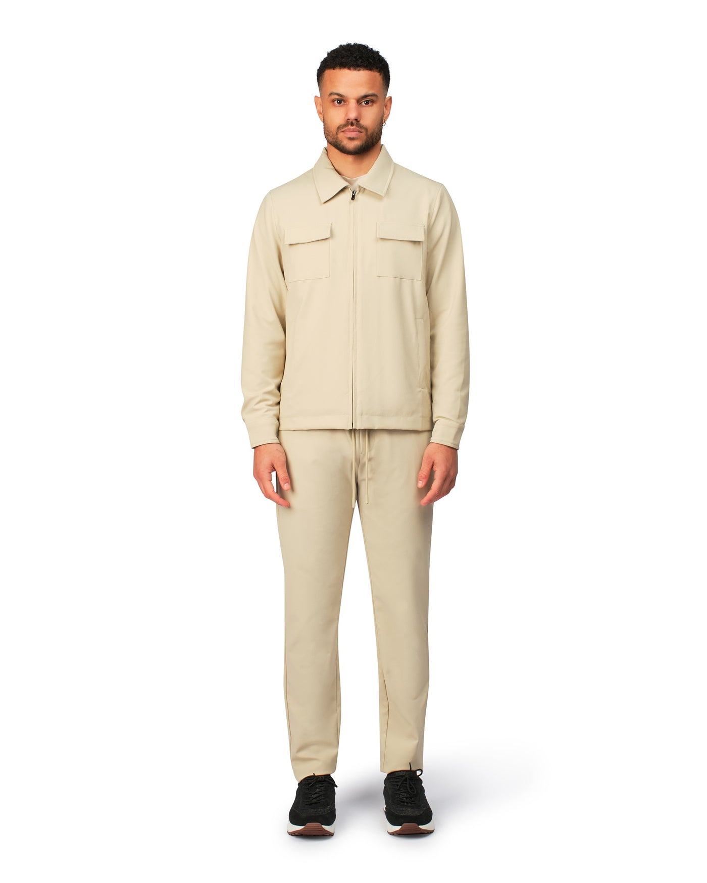 Man wearing a beige jacket and pants on a white background