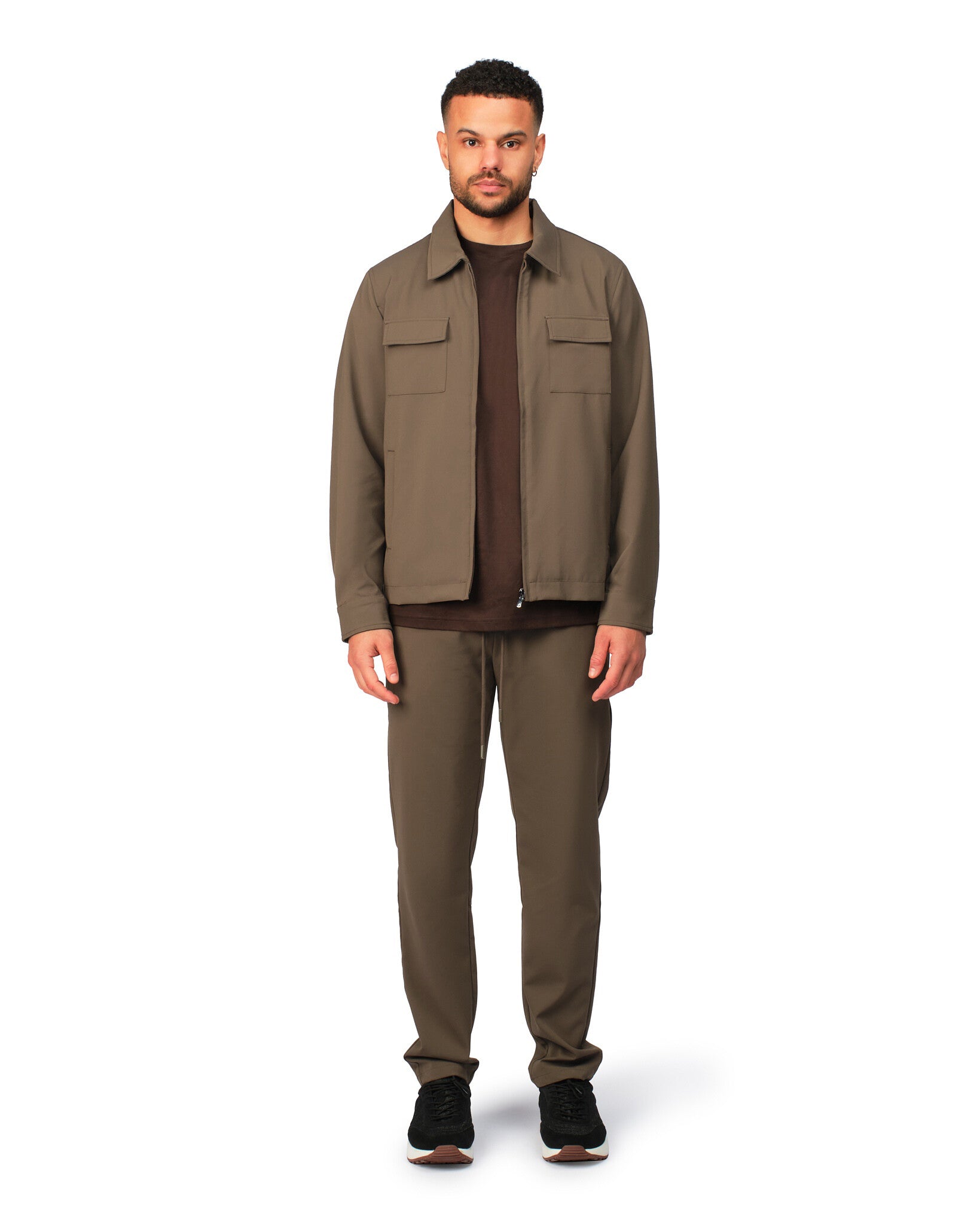 Man wearing a brown jacket and pants on a white background
