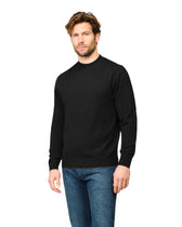 Man wearing a black sweater and blue jeans on a white background