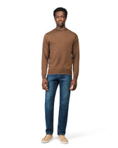 Man wearing a brown sweater and blue jeans on a white background