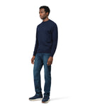 Man wearing a navy long-sleeve shirt and blue jeans on a white background