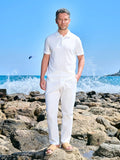 Man in an ivory polo and white trousers on a rocky shore
