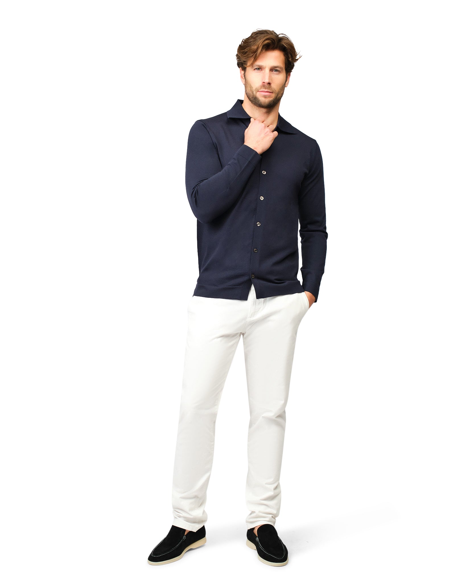 Man wearing a navy blue shirt and white pants on a white background