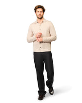 Man wearing a beige sweater and black pants on a white background