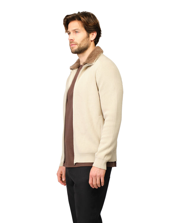 Man wearing a beige and brown jacket with fur lining on a white background