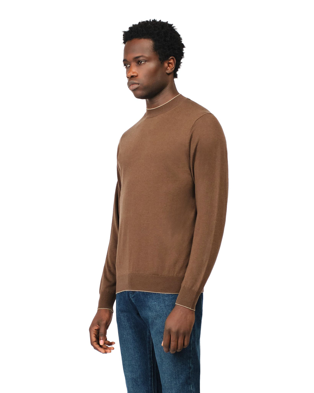 Man wearing a brown sweater and blue jeans on a white background