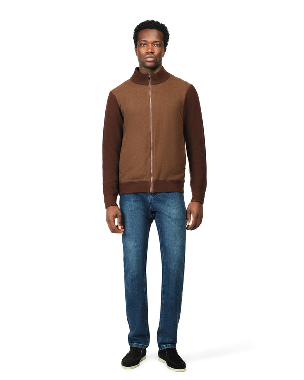Man wearing a brown jacket and blue jeans on a white background