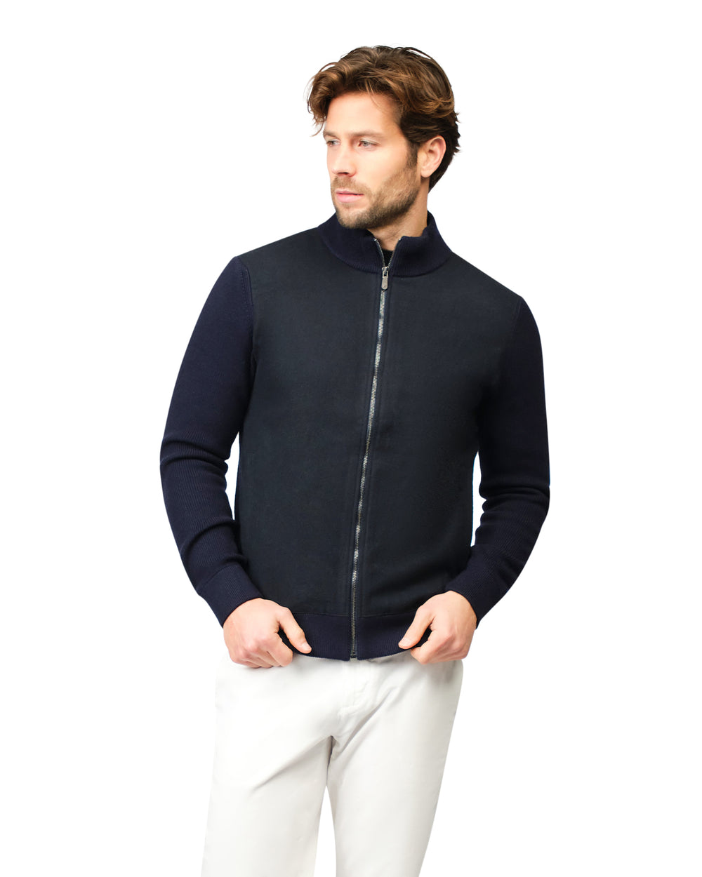 Man wearing a navy blue zip-up sweater over a white shirt on a white background