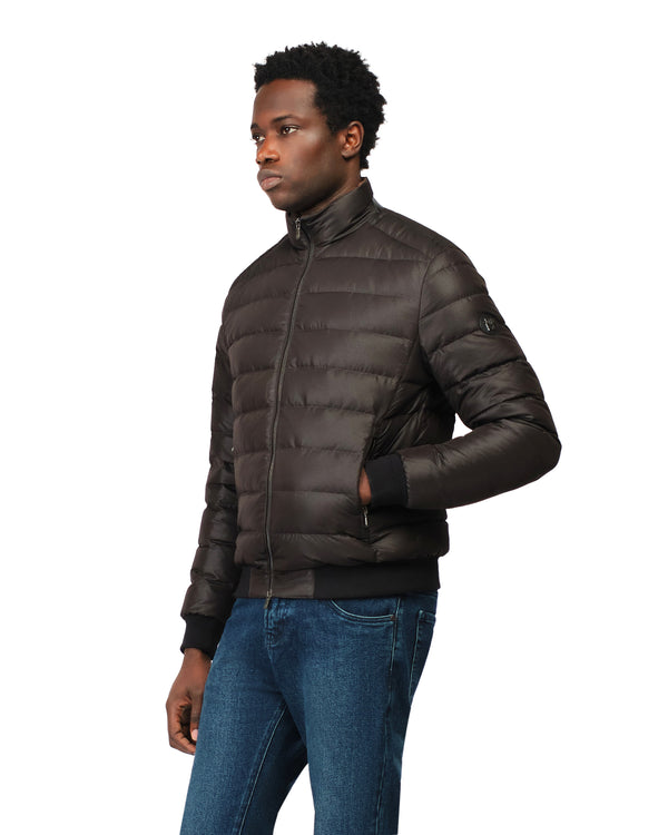 Man wearing a brown puffer jacket and blue jeans on a white background