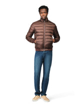 Man wearing a brown puffer jacket and blue jeans on a white background