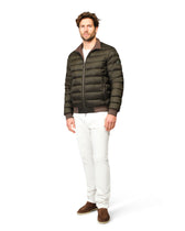 Man wearing a green puffer jacket and white pants on a white background