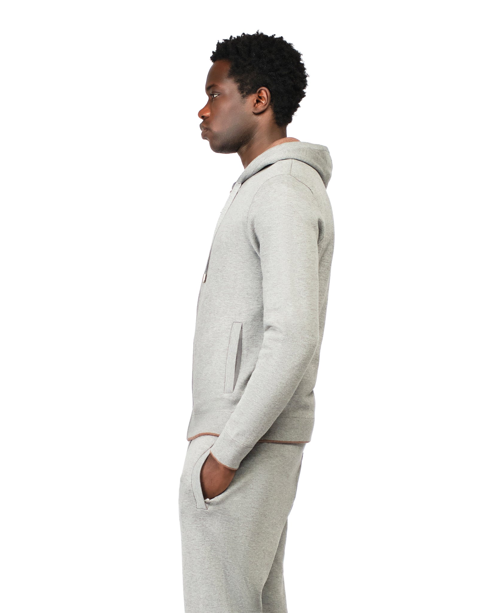 Person wearing a gray hoodie and pants on a white background