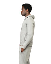 Person wearing a gray hoodie and pants on a white background