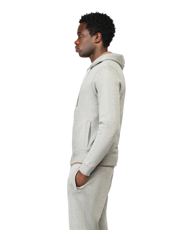 Person wearing a gray hoodie and pants on a white background