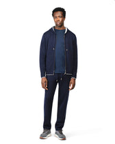 Man wearing a navy tracksuit on a white background