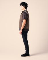 Person wearing a brown shirt and black pants on a beige background