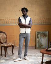 Man standing in a room with ornate wall patterns and vintage furniture.